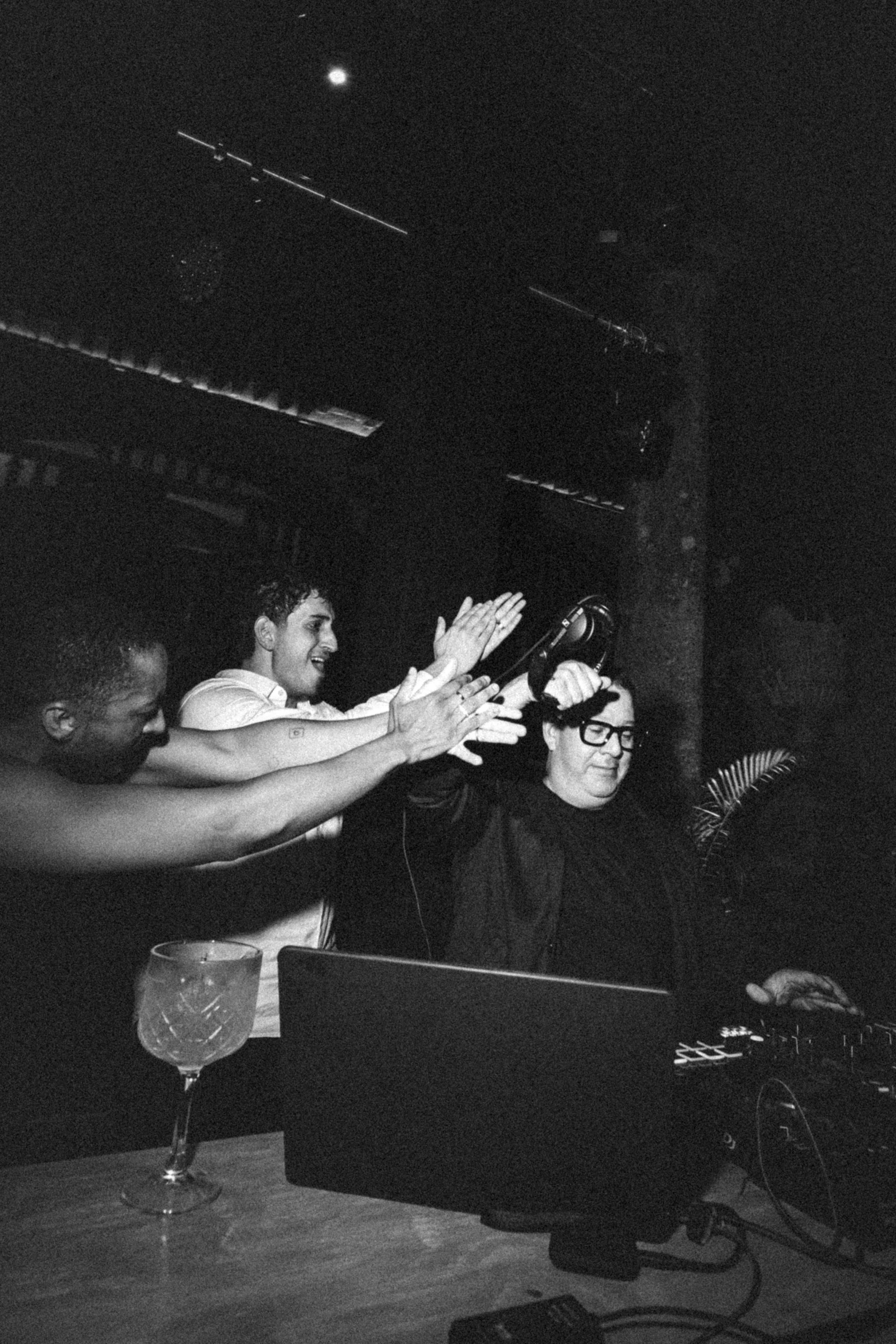 Moncho DJing while wedding guests celebrate beside the booth